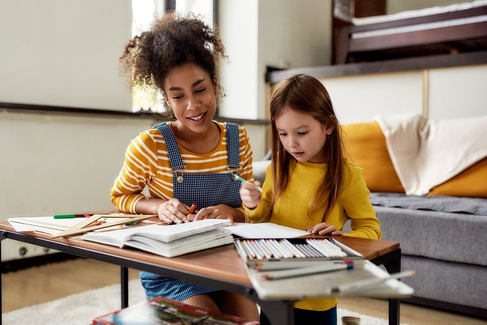 Une adulte accompagne une enfant pendant ses devoirs